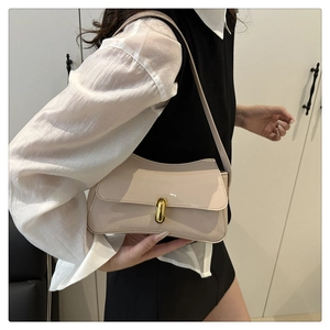 Side view of a retro beige underarm bag with gold clasp on a model's shoulder