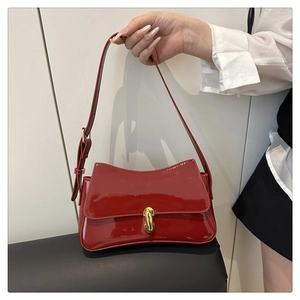 Detail of red patent leather shoulder bag with elegant gold metal twist lock buckle