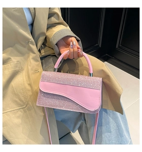 Detail of pink rhinestone saddle bag with curved flap and leather handle for women