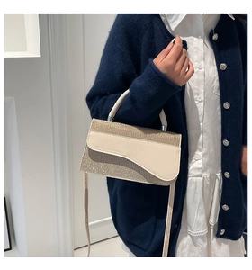Detail of the glittery beige crossbody bag with a unique asymmetrical flap design