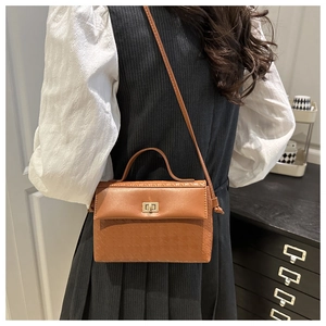 Brown leather crossbody bag with square embossed pattern and gold clasp on model