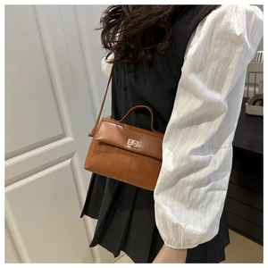 Detail of retro brown contrast handbag featuring woven texture and gold twist lock closure
