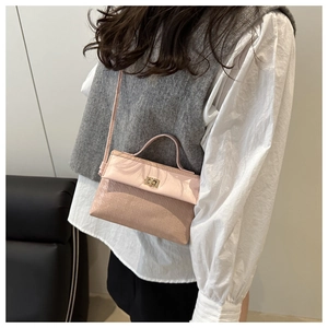 Detail of pink mini textured handbag with gold twist lock worn with a white shirt