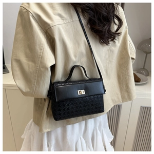 Detail of black winged Kelly bag with gold metal lock and houndstooth texture