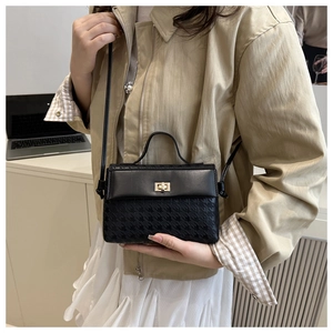 Detail of black crossbody bag with houndstooth texture and golden twist lock closure