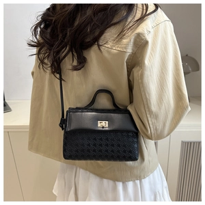 Detail showing the black crossbody bag with houndstooth texture on a stylish model