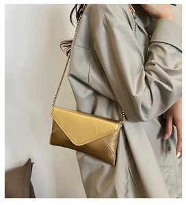 Close-up of golden metallic chain bag with V-shaped flap on a female model