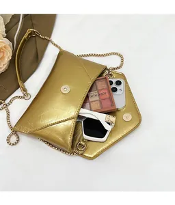 Detail view of gold chain crossbody envelope bag showing spacious interior and metallic texture