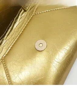 Detail of durable gold magnetic snap closure on textured metallic envelope crossbody bag