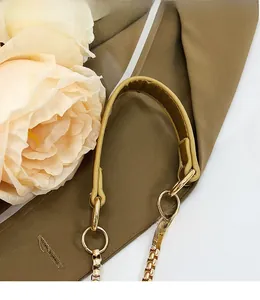 Detail of smooth yellow faux leather shoulder strap with gold metal chain and buckle