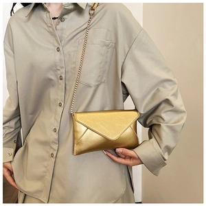 Detail of the golden metallic textured envelope bag with V-flap and chain strap