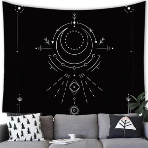 Modern black and white celestial tapestry with moon and star patterns above a sofa