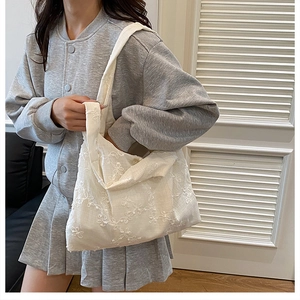 Détail de la broderie florale blanche sur tote bag porté avec une tenue d'école