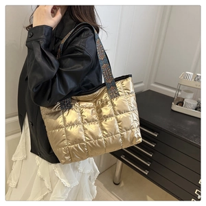 Detail der gold gesteppten Tragetasche mit Metallic-Textur und gemustertem Riemen