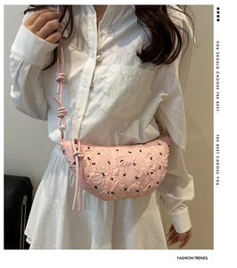 Detail shot of a pink crescent-shaped quilted bag with bow patterns and knotted strap