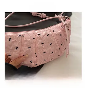 Close-up of pink embossed texture bag with black bow embroidery and slim strap