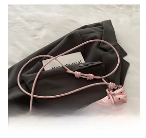 Detailed close-up of a pink crescent bag with black bow patterns on grey suit