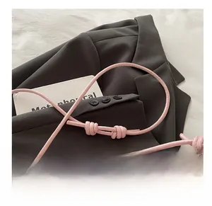 Detail of a thin pink shoulder strap with a decorative knot on a stylish handbag