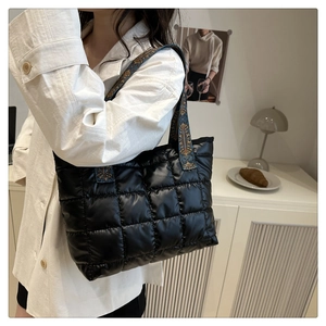 Détail du sac cabas matelassé noir avec bandoulière jacquard ethnique porté à l'épaule