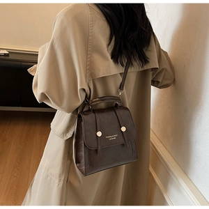 Detail of vintage brown leather handbag with metallic buckles and adjustable strap