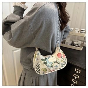 Close-up of floral crescent shoulder bag with metallic chain strap and leather patch