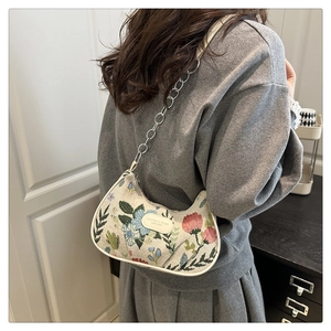 Close-up of crescent nylon bag with floral embroidery and silver metal chain strap