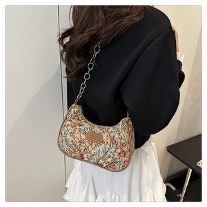 Detailed macro view of the vintage floral jacquard fabric and silver chain on hobo bag