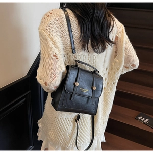 Detail of black textured PU leather backpack with gold buckle and adjustable straps