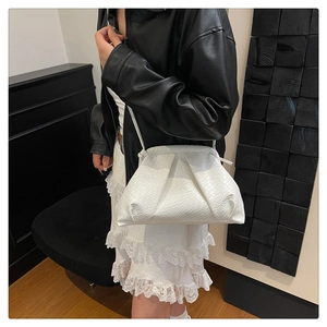 Detailed macro view of white woven textured cloud bag with elegant pleats and shoulder strap