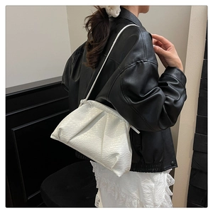 Detail of white woven textured cloud bag featuring a pleated design and slim leather strap
