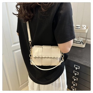 Detail of cream woven crossbody bag with wavy texture and adjustable strap on model