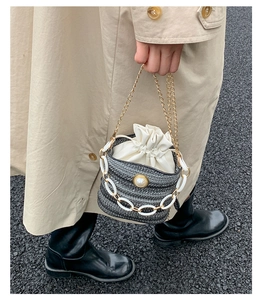 Detail of tweed bucket bag with decorative pearl chain and golden metal handle
