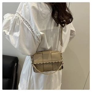 Detail view of khaki woven crossbody bag with scalloped edge and gold chain strap