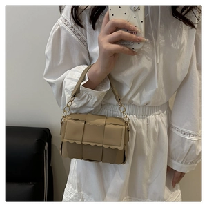 Close-up of woven texture and wavy scalloped edge detail on beige crossbody bag