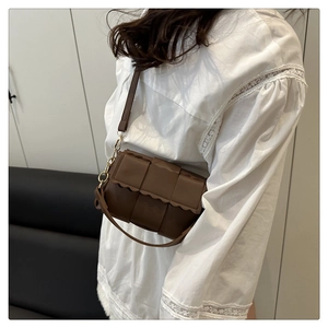 Detail of coffee brown woven crossbody bag with wavy edge flap and gold hardware hooks