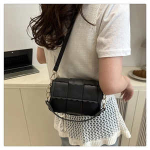 Detail of black woven shoulder bag with unique scalloped edges and gold chain strap links