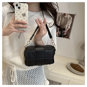 Detail of black woven PU leather crossbody bag with wave edges and gold metal ring hardware