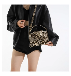 Detail of leopard print crossbody bag with golden V-shaped buckle and textured PU leather