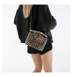 Detail of crossbody bag with classic leopard print and gold V-shaped metal logo