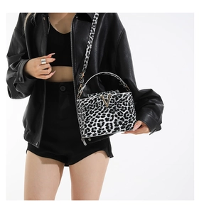 Detail of leopard print handbag with gold V buckle and textured faux leather finish