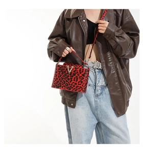 Close-up of leopard print handbag featuring a glossy finish and a golden V-shaped metal logo