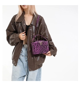 Detail of purple leopard print shoulder bag with gold V-logo and long strap on model