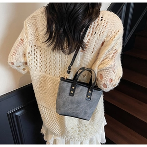 Detailed view of a dark grey bucket bag with vintage matte texture on wooden stairs