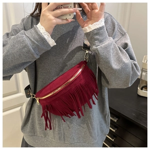 Detail of burgundy fringe crossbody bag with suede finish and patterned shoulder strap