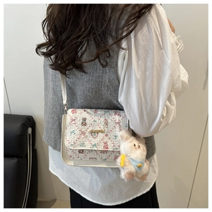 Detailed back view of white crossbody bag with floral bear print and plush bunny charm