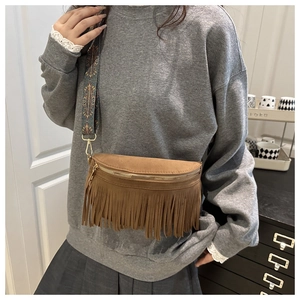 Detail of brown suede tassel crossbody bag with vintage bohemian ethnic patterned strap