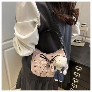 Detailed close-up of pink ruched fabric bag with black bow patterns and cute bear charm