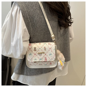 Detail of white leather crossbody bag with cartoon prints and plush cat charm accessory
