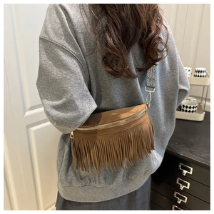 Detail view of brown suede crossbody bag with long fringes and vintage patterned strap