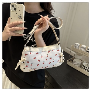 Detail of white baguette bag with cherry print and decorative side bow detail